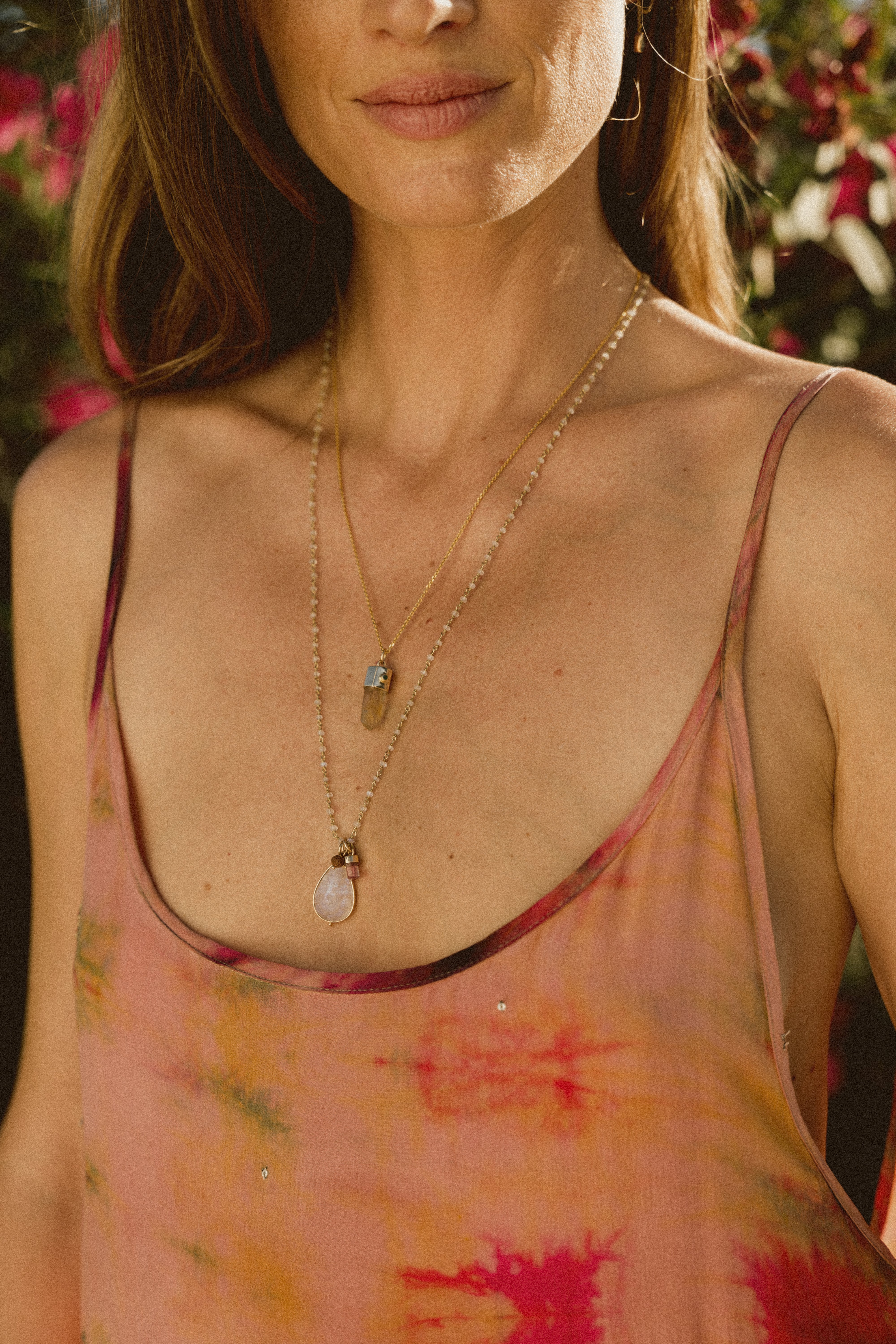 A model in a pink floral dress wearing a moonstone necklace