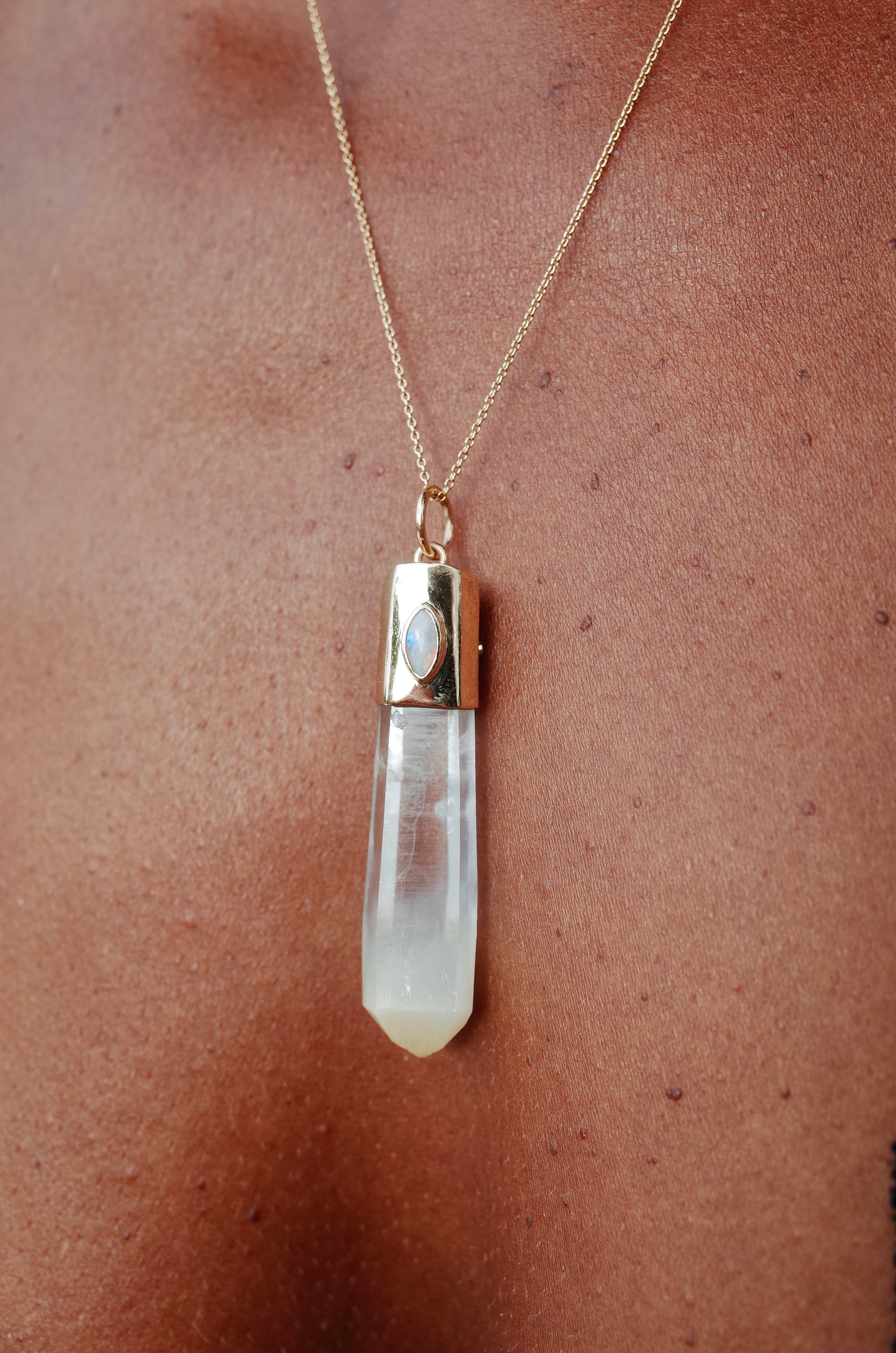 Crystal amulet in mango quartz with inlayed opal shown on a person's chest