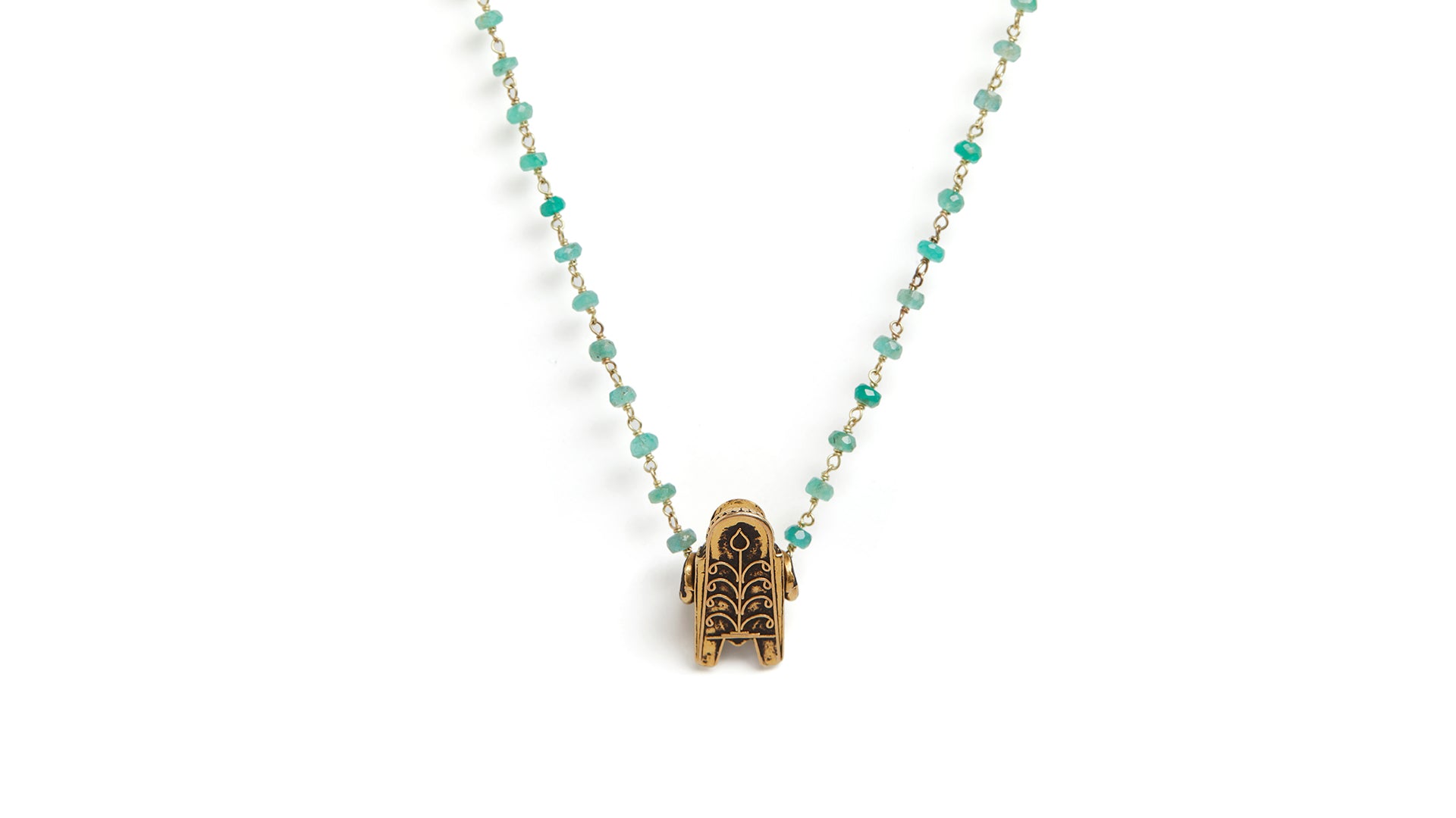 Backside of gold Thali pendant on a beaded emerald necklace against a plain white background