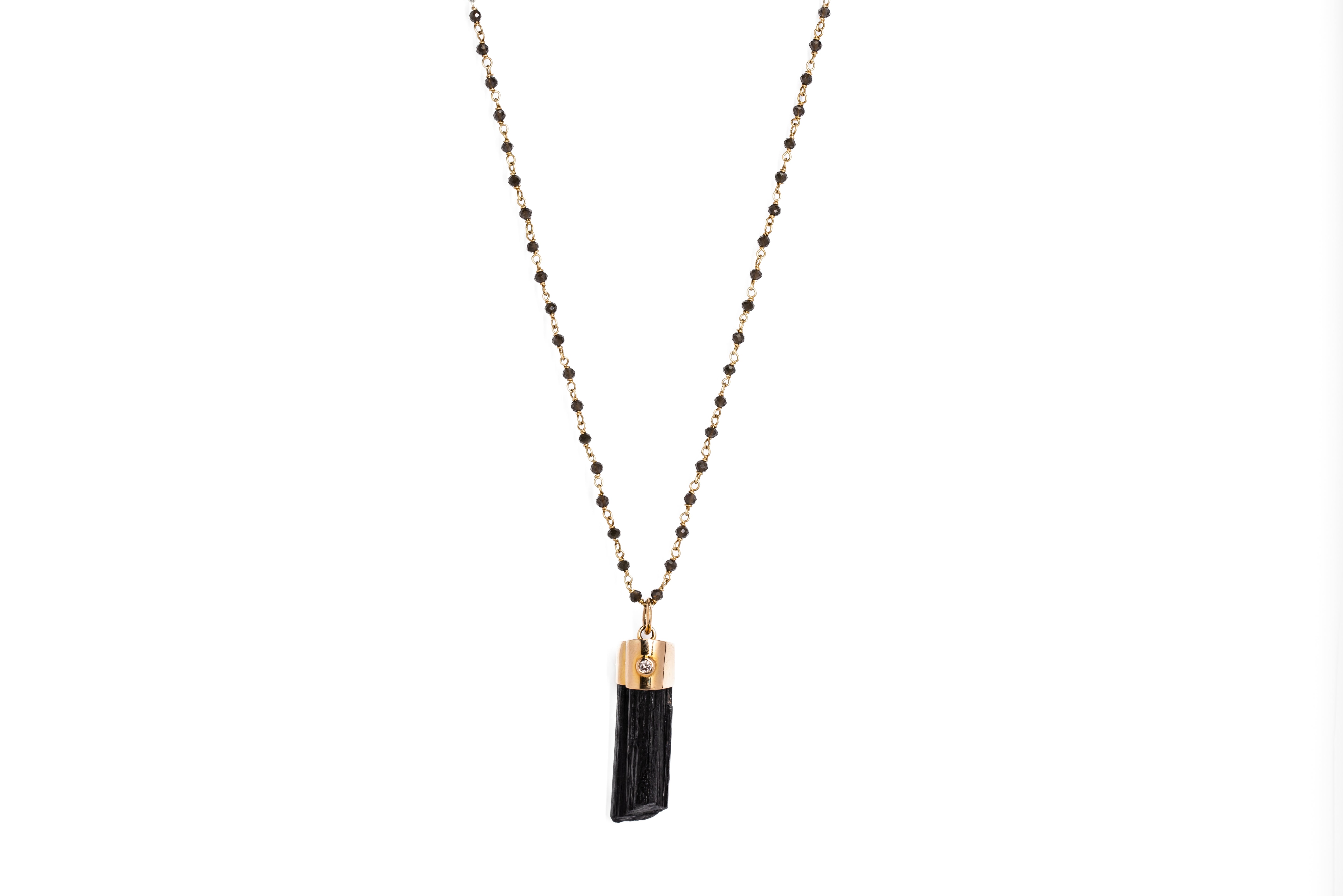 A Black Tourmaline Necklace with small black beads and gold accents and a gold capped black tourmaline pendant displayed against a white background.