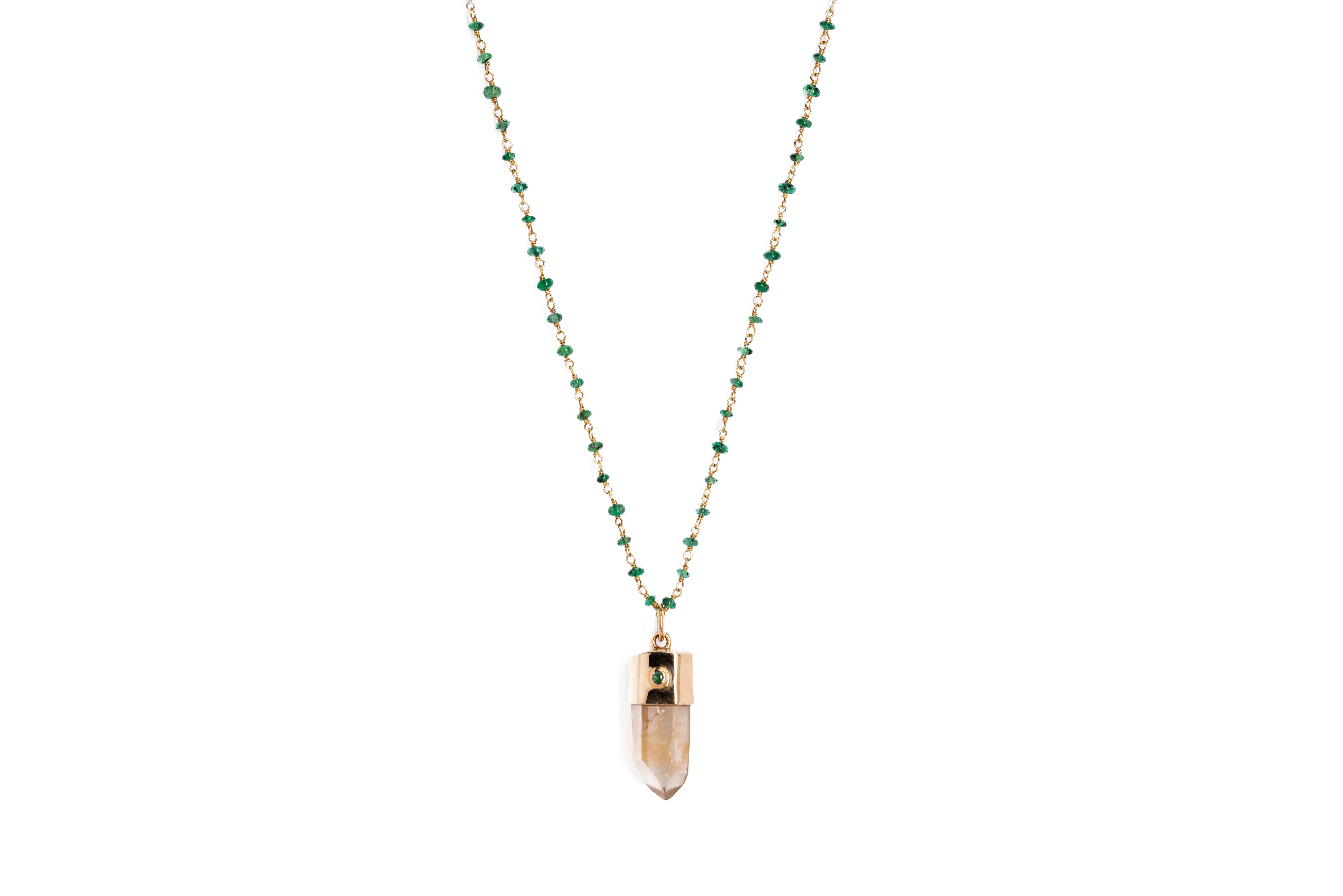 A beaded emerald necklace in 18ct gold  with a gold capped crystal pendant on a plain white background
