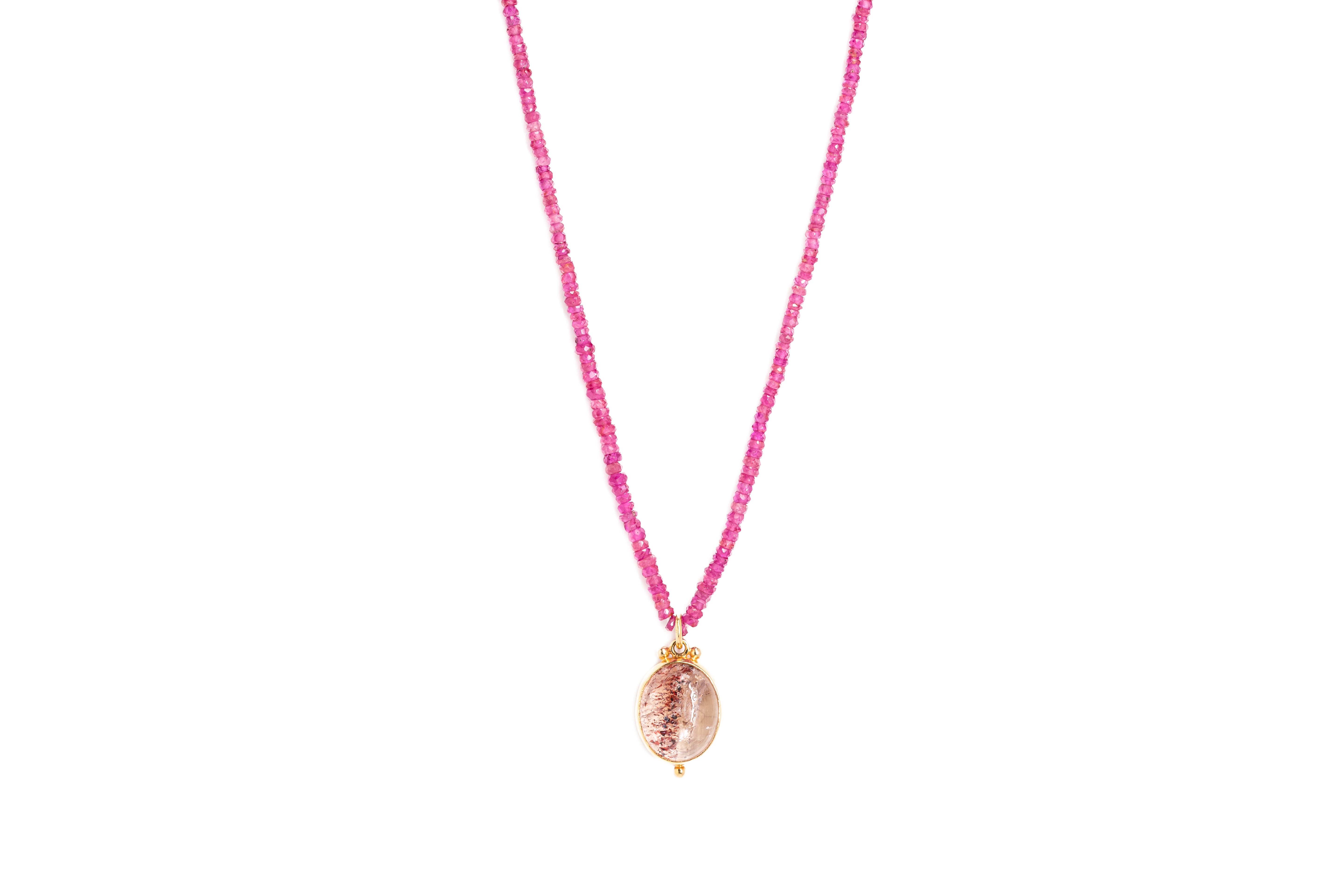 A beaded ruby necklace with pendant against a white background