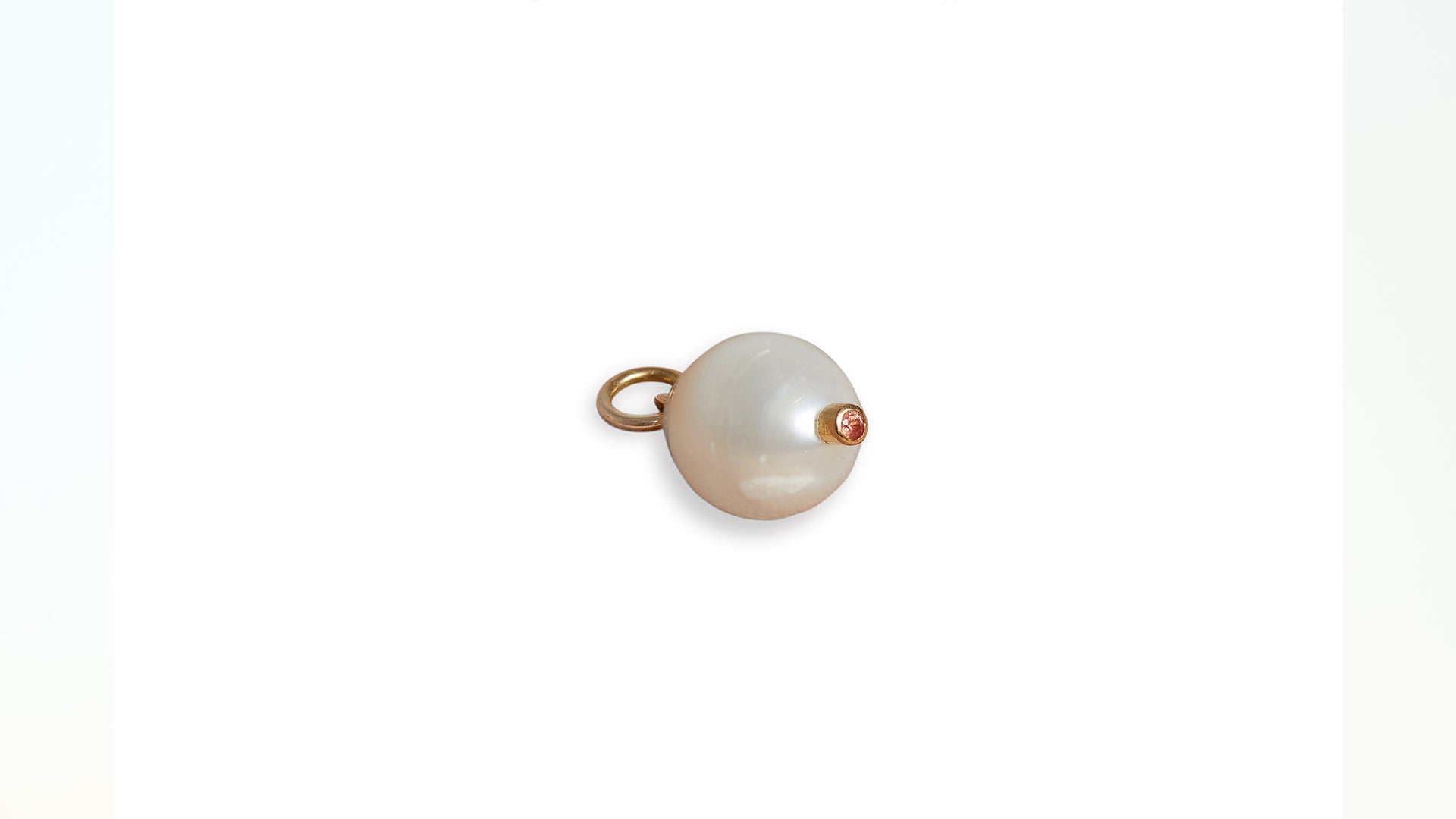 A view of the bottom of the pearl and orange sapphire charm pendant against a white background