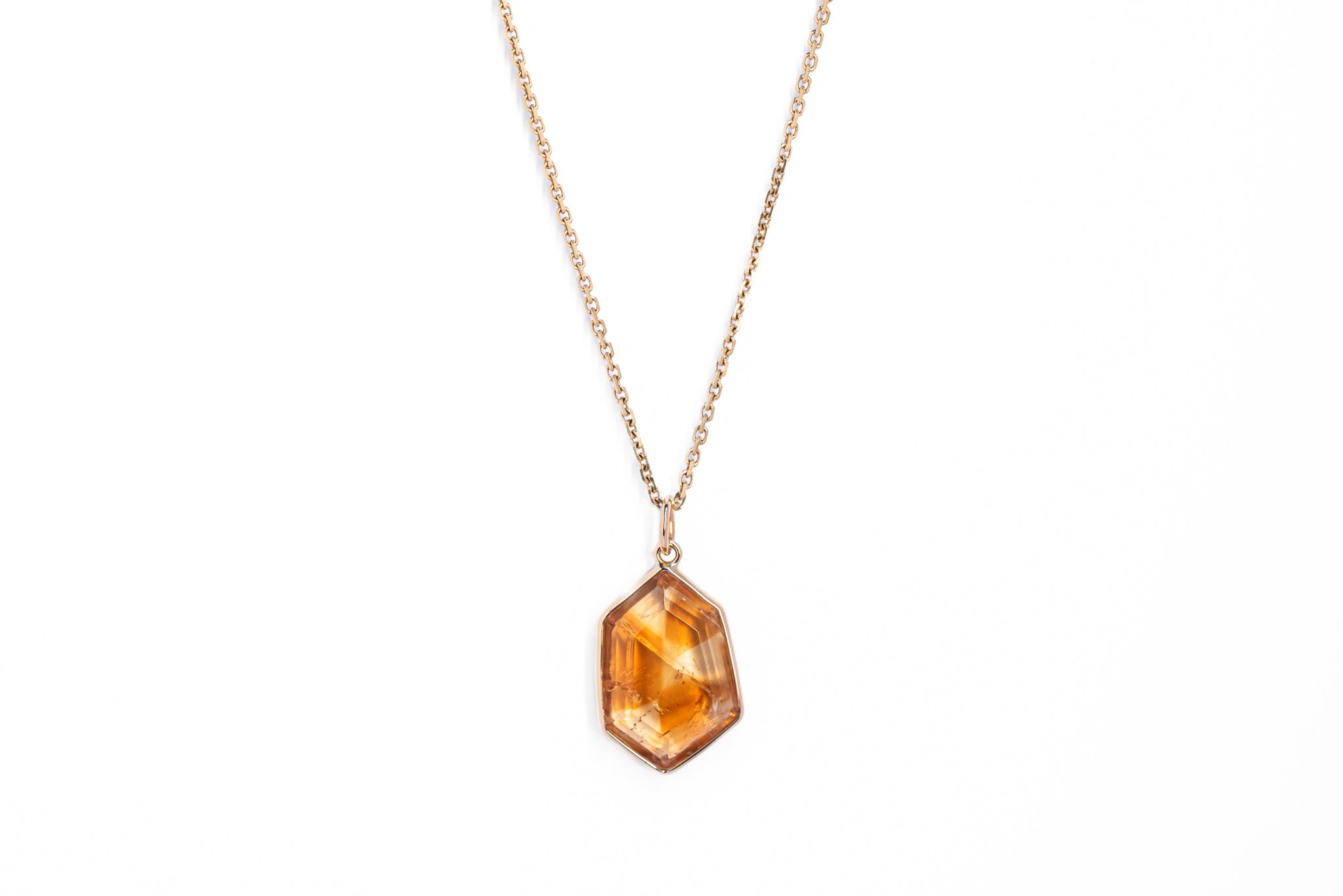 A gold-colored pendant featuring a citrine crystal in a window-shaped setting.