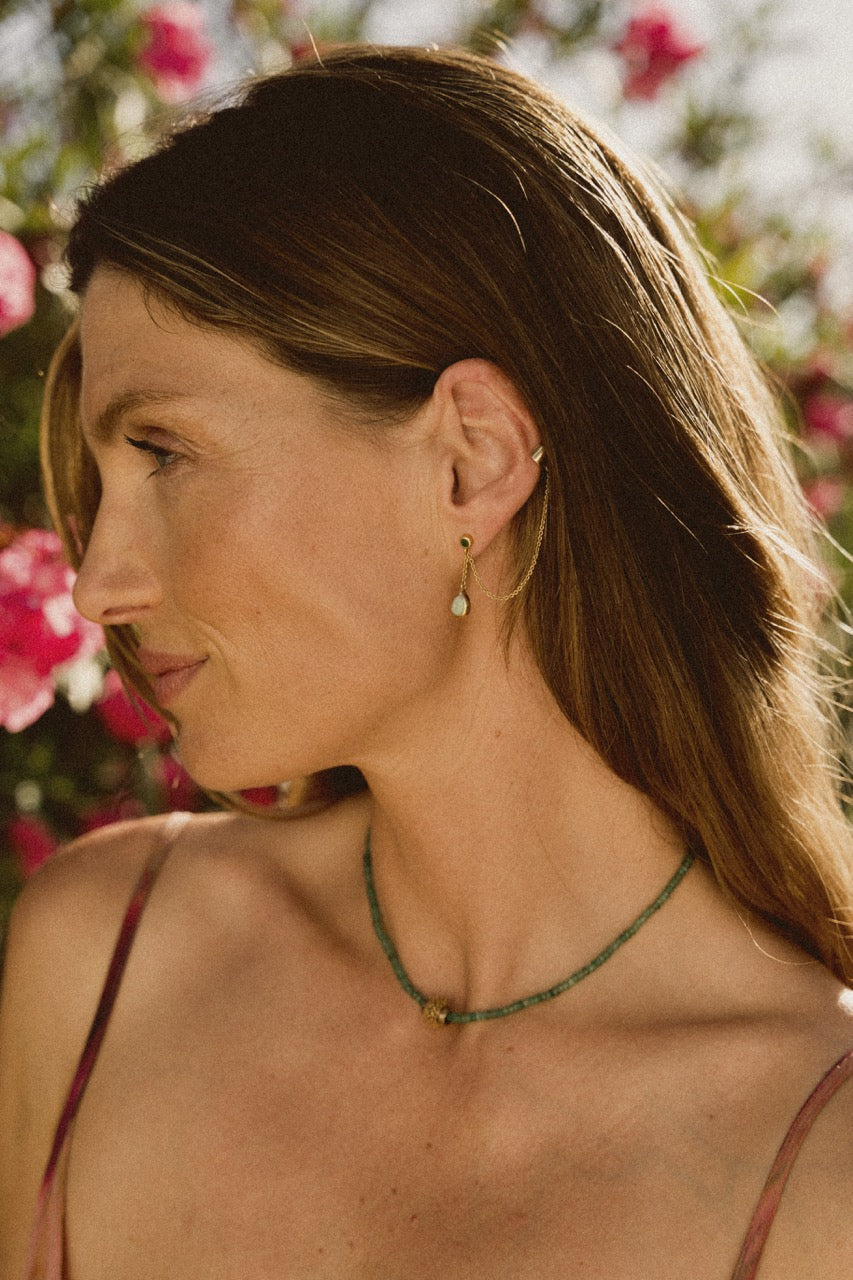 A model wearing a beaded emerald necklace looking to the side