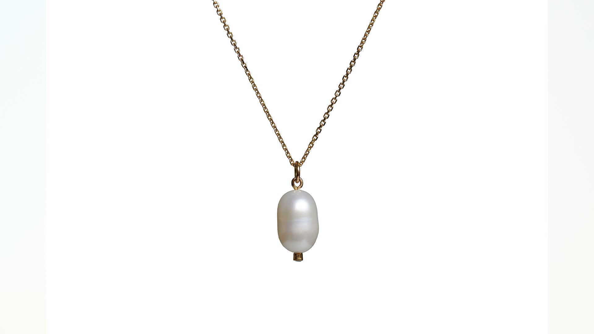 A pearl and ruby charm pendant on a gold chain against a white background.