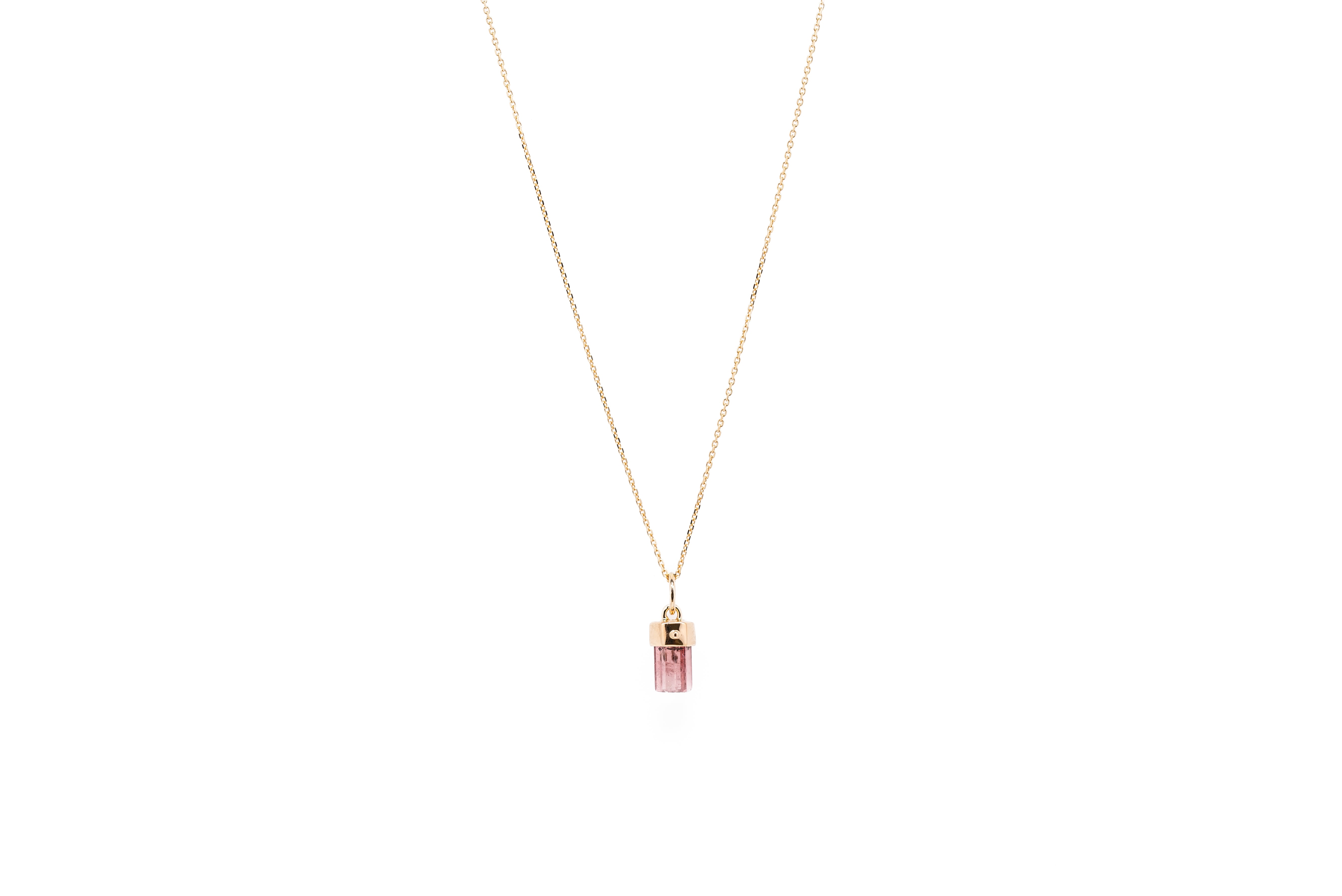 A pink tourmaline baby amulet necklace with a gold chain against a white background