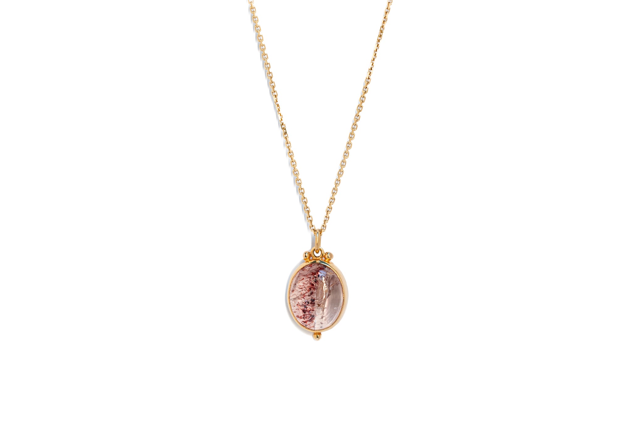A Super Seven crystal amulet pendant on a gold chain against a white background